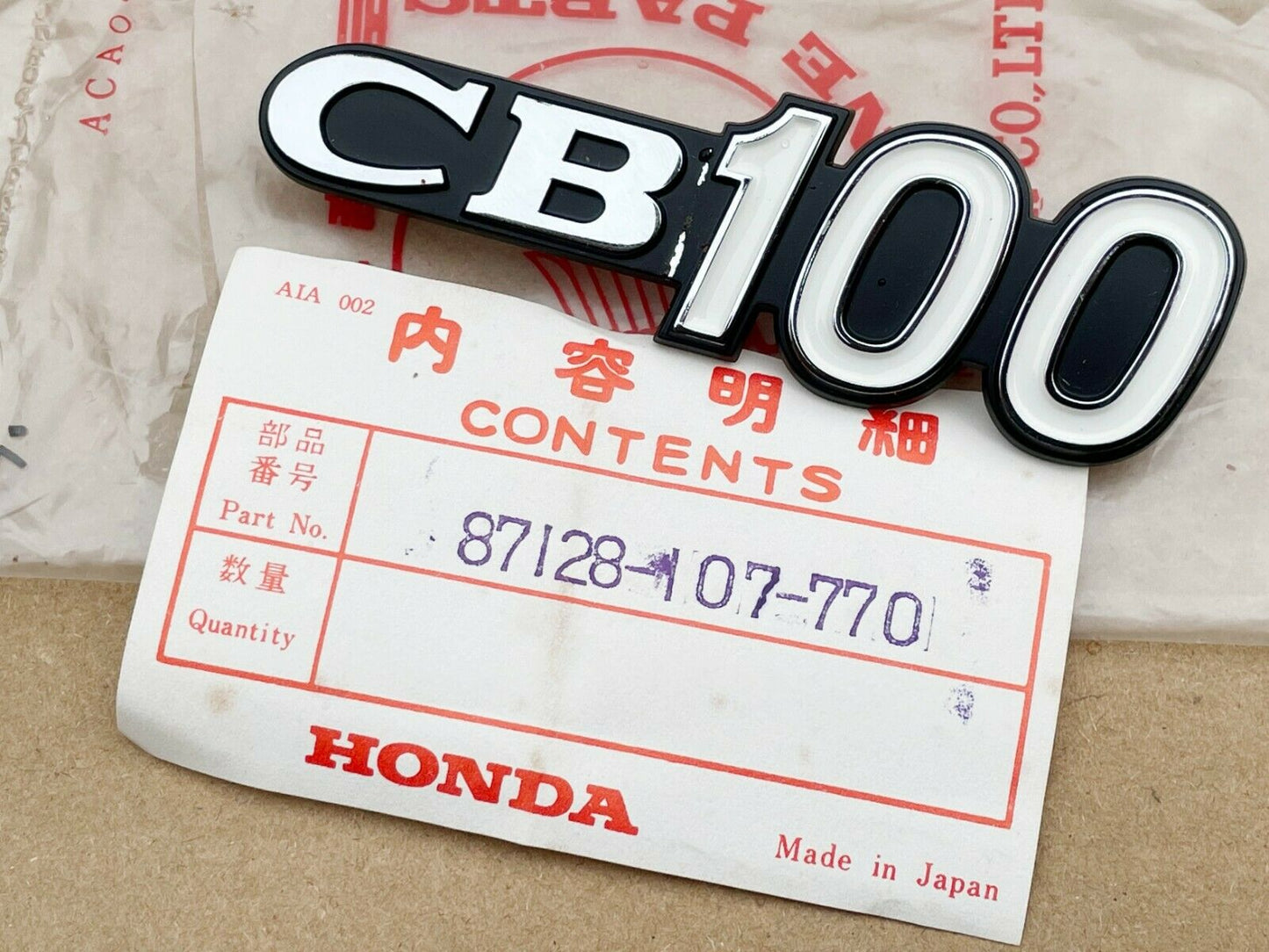 Honda CB100 NOS Sidecover Badge 87128-107-770 sku 6220